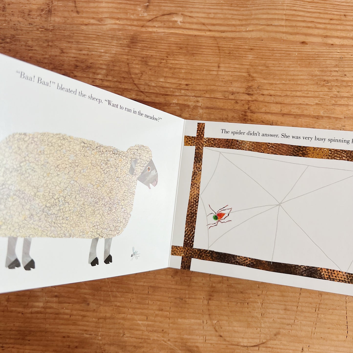 Interior spread of The Very Busy Spider showing a woolly white sheep on the left page beside text reading "Baa! Baa!" bleated the sheep. "Want to run in the meadow?", and the spider spinning her raised tactile web on the fence post on the right page, with text reading "The spider didn't answer. She was very busy spinning her web"
