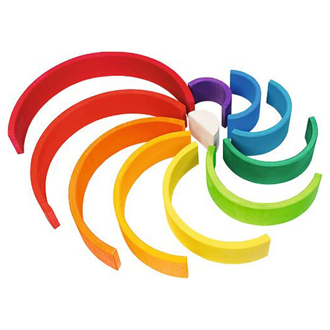 Goki Rainbow Building Blocks arranged in a flat pinwheel formation on a white background, with all 11 arches fanned out from a central natural wood piece to show the full spectrum of hand-painted colors from red through orange, yellow, green, lime, teal, blue, and purple