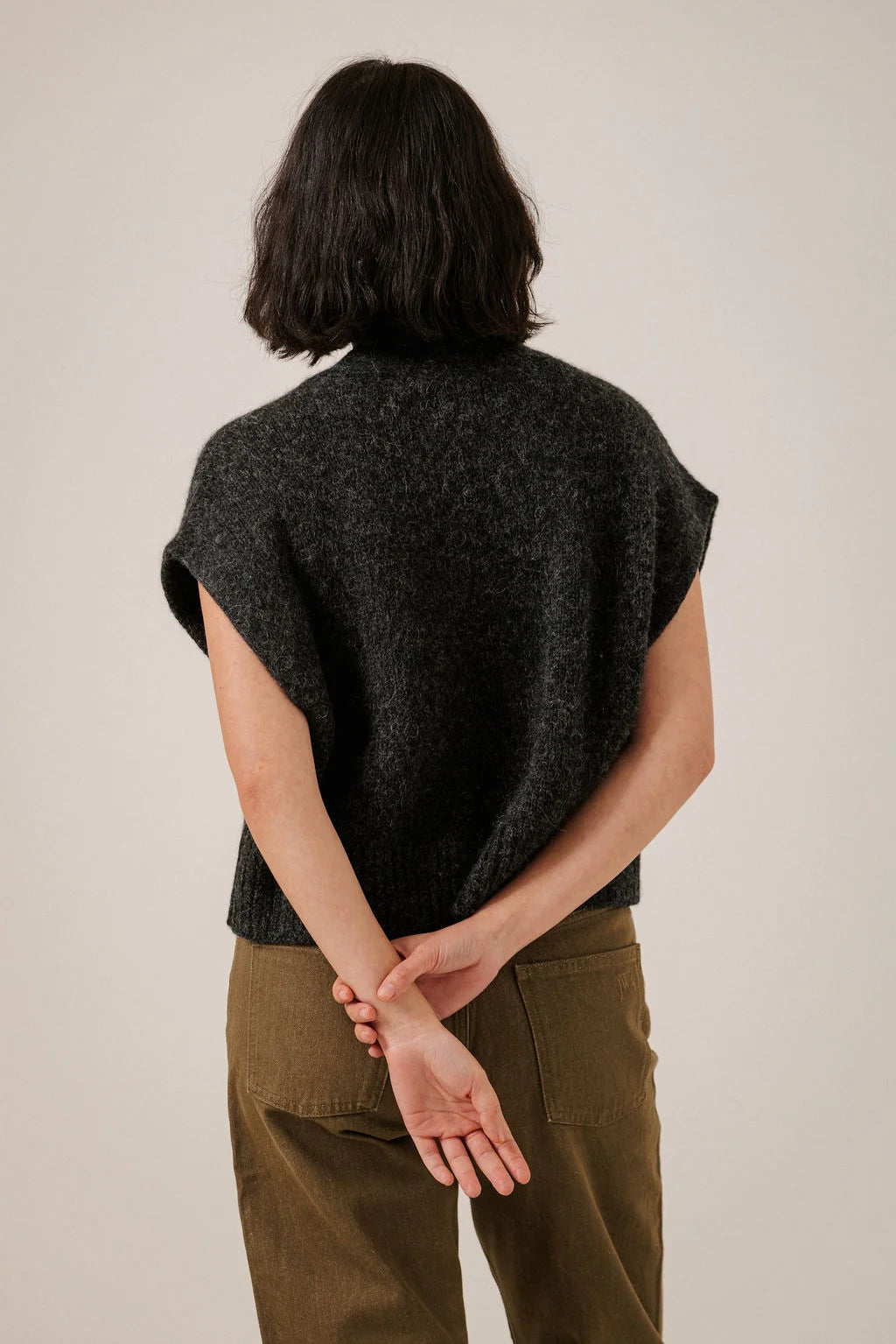 Back view of the Basalt vest on a model, showing its relaxed shape and textured dark knit.