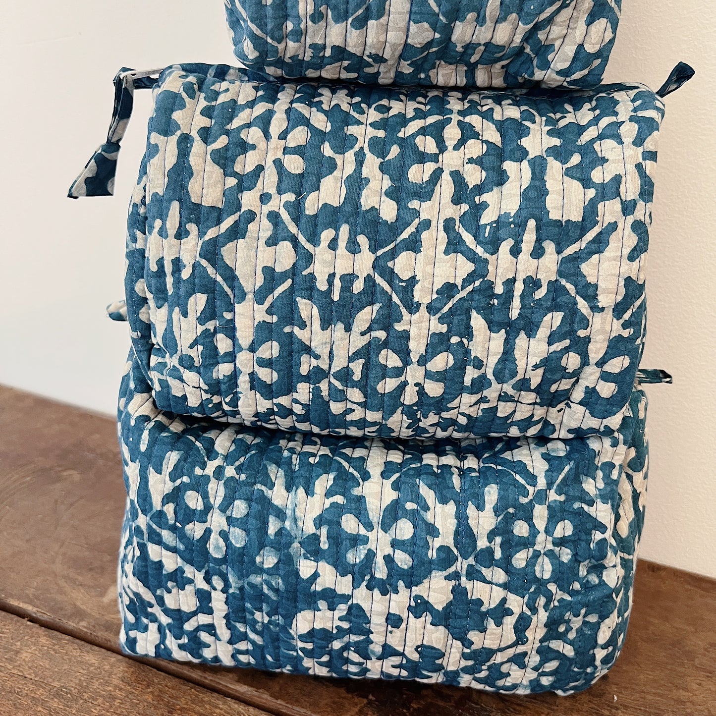 Close-up of the Toiletry Bag in Isla Blockprint showing the cream quilted cotton with a teal floral tile block-print motif and vertical quilting stitches