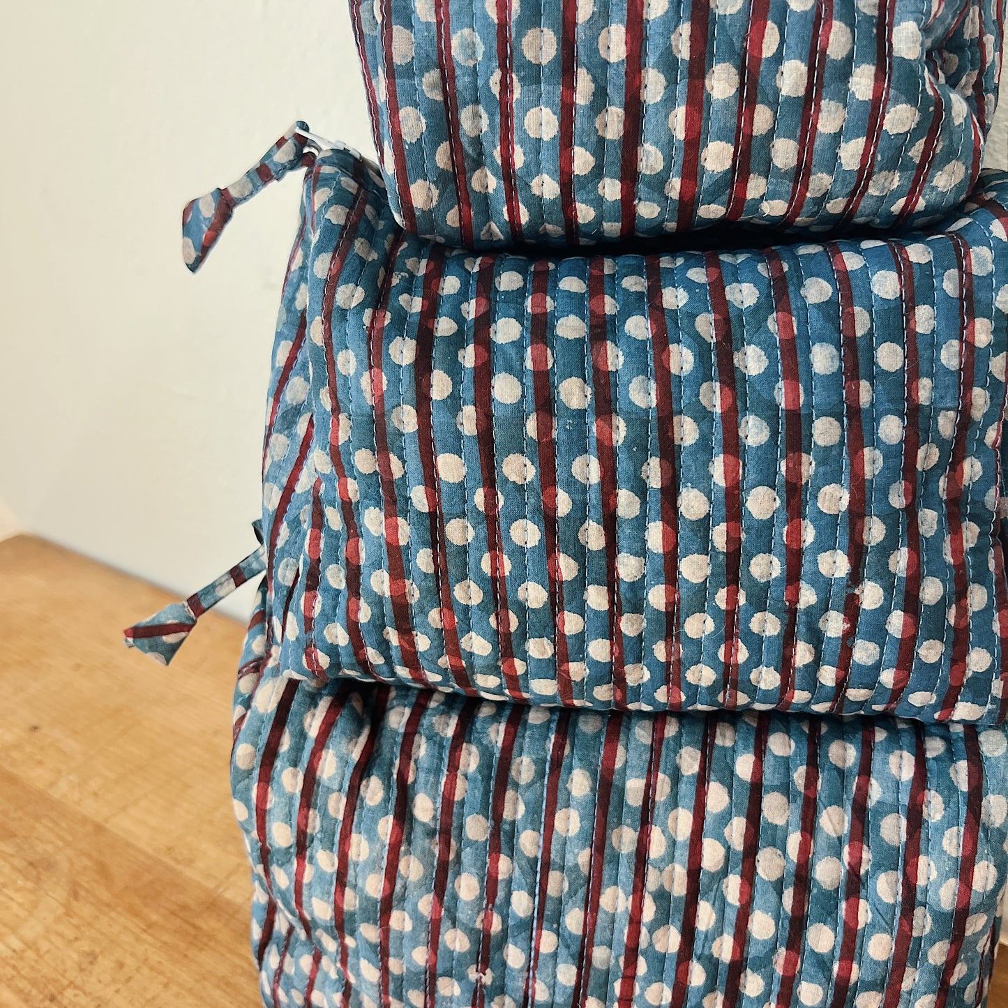 Close-up of the Toiletry Bag in Persephone Blockprint showing the slate blue quilted cotton with burgundy stripe and white polka dot block-print motif and vertical quilting stitches
