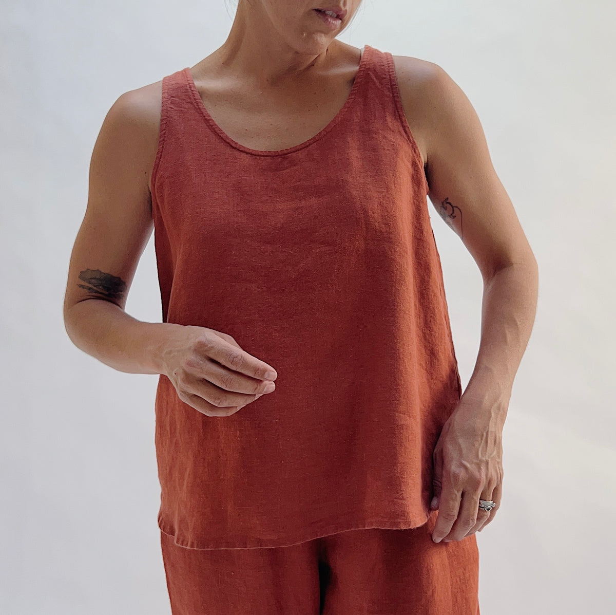 Front view of the Basic Tank in Terracotta by Yuvita — a cropped 100% linen scoop-neck tank in warm terracotta, styled with matching terracotta linen pants and gold hoop earrings