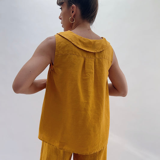 Back view of the Sailor Tank in Turmeric by Yuvita, showing the sailor collar, relaxed linen drape, and curved hem in golden turmeric yellow, styled with matching linen wide-leg pants