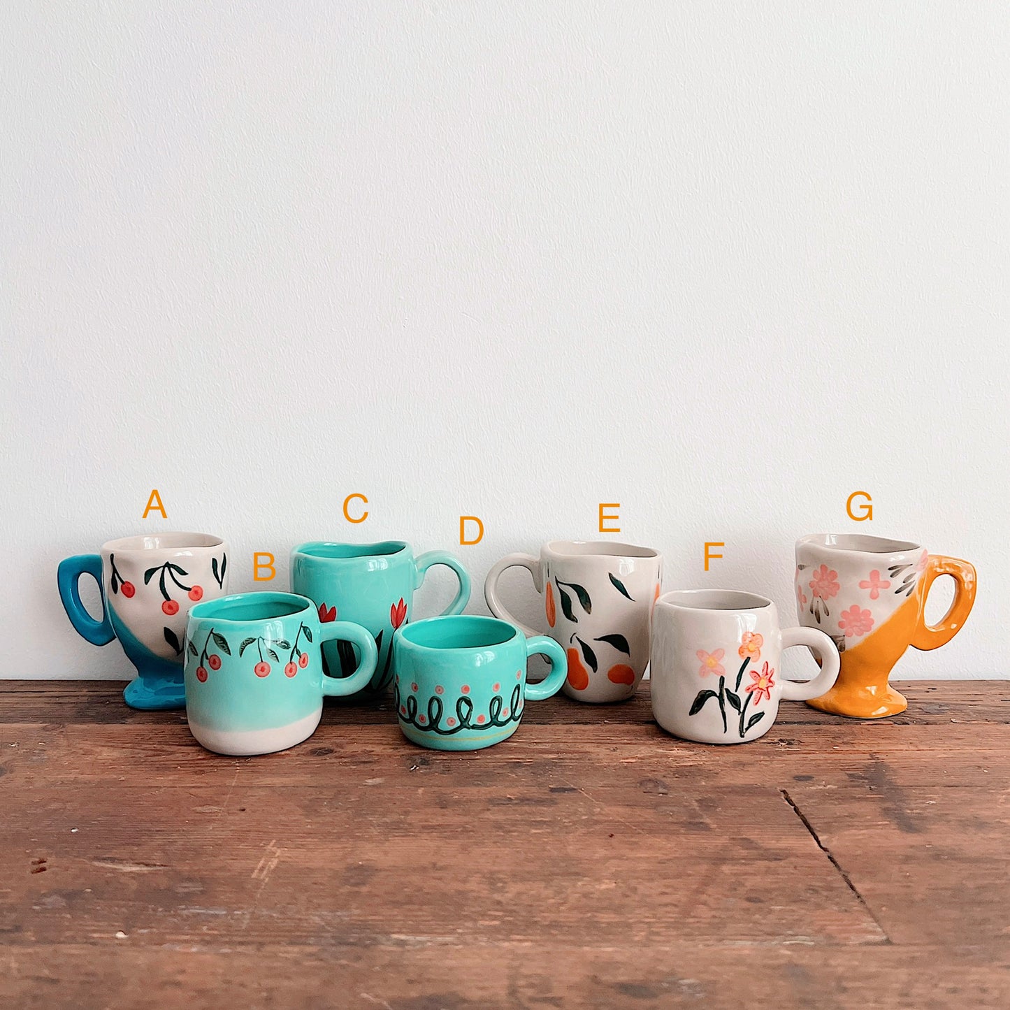 Mug selection guide: A, blue-footed cherries; B, turquoise cherries; C, turquoise tulips; D, turquoise loops; E, cream fruit; F, cream flowers; G, yellow-footed flowers.