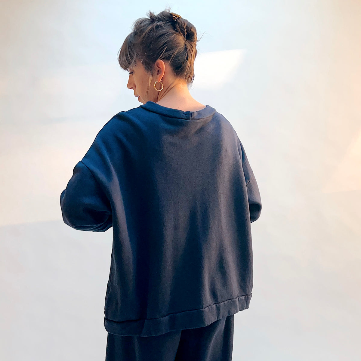 Angled back view of Alden Fleece Sweatshirt in Nova on a model, showing the loose silhouette, dropped shoulders, and banded hem.