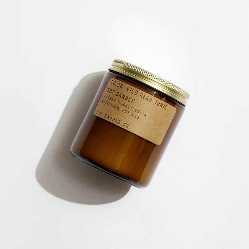 P.F. Candle Co. Wild Herb Tonic soy candle in an amber glass jar with a kraft label and brass-colored lid.