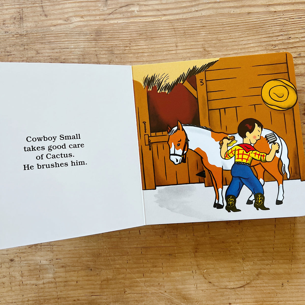 Interior spread of Cowboy Small showing an illustration of Cowboy Small brushing his horse Cactus in a barn, beside text reading "Cowboy Small takes good care of Cactus. He brushes him."
