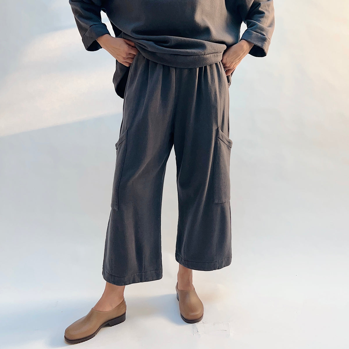 Front view of Pasha Fleece Pant in Moonlight with the model holding the sweatshirt above the gathered waistband.
