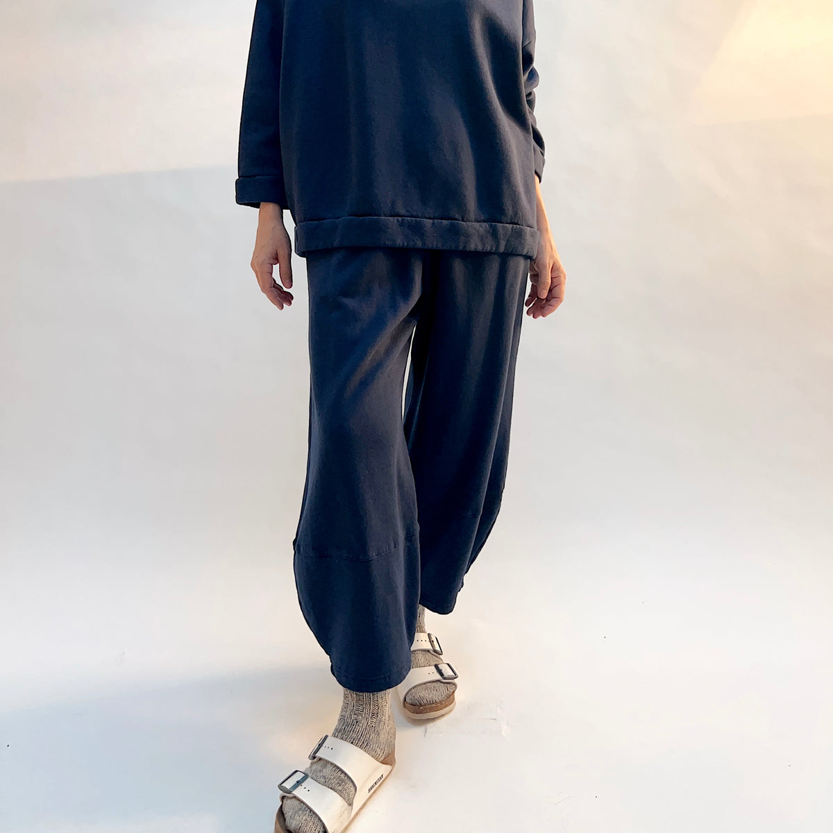Model stepping forward in Oliver Fleece Pant in Nova, showing the drape and curved leg silhouette.
