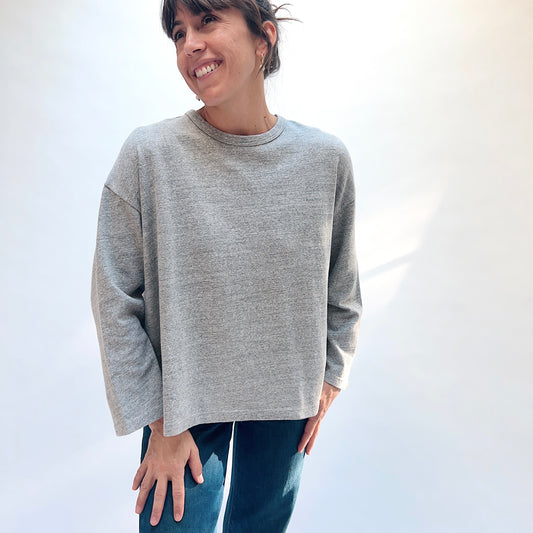 Front view of a model wearing the grey cotton knit pullover with a round neckline and dropped shoulders.
