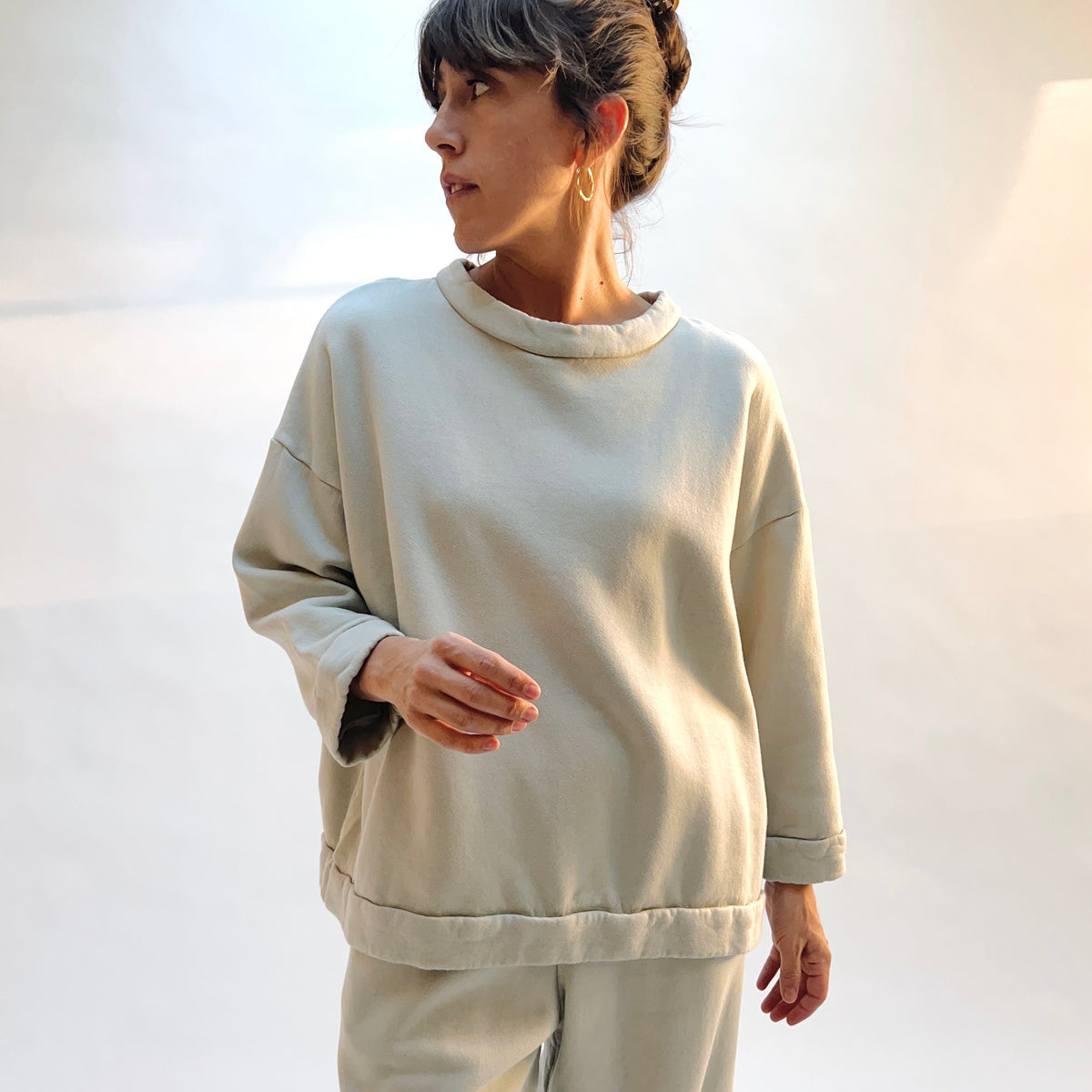 Front view of Bryn Walker Alden Fleece Sweatshirt in Orlaya on a model, showing the draped neckline, dropped shoulders, and banded hem.
