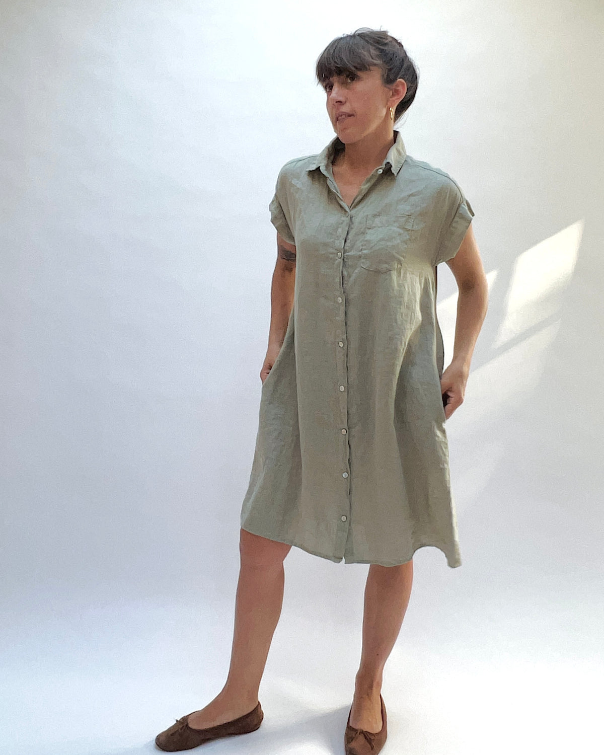 Cut Loose Hanky Linen Cap Sleeve Shirt Dress in Balsam Green, front view with model's hands in the side pockets.
