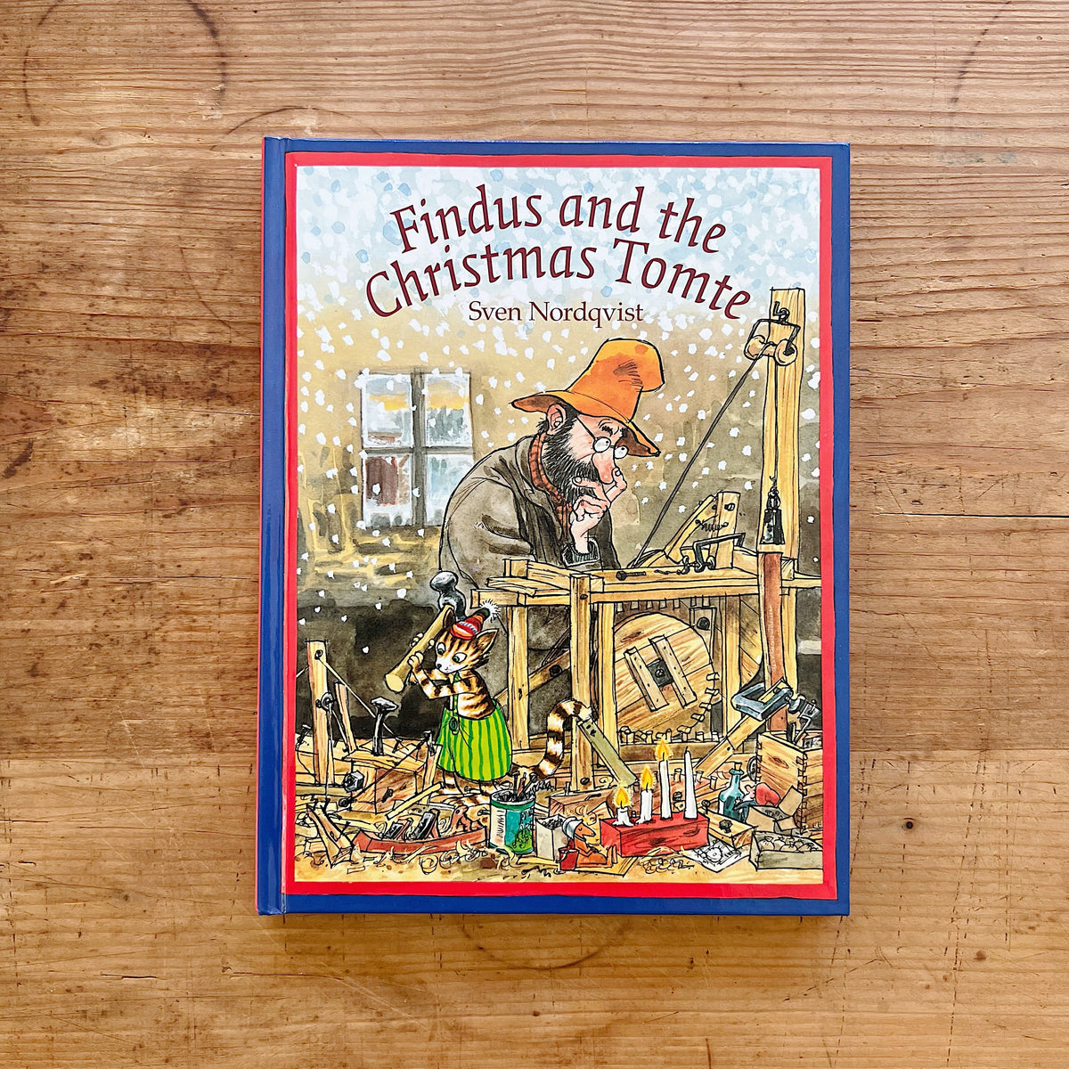 Front cover of Findus and the Christmas Tomte by Sven Nordqvist, showing Pettson and Findus beside a wooden mechanical invention.
