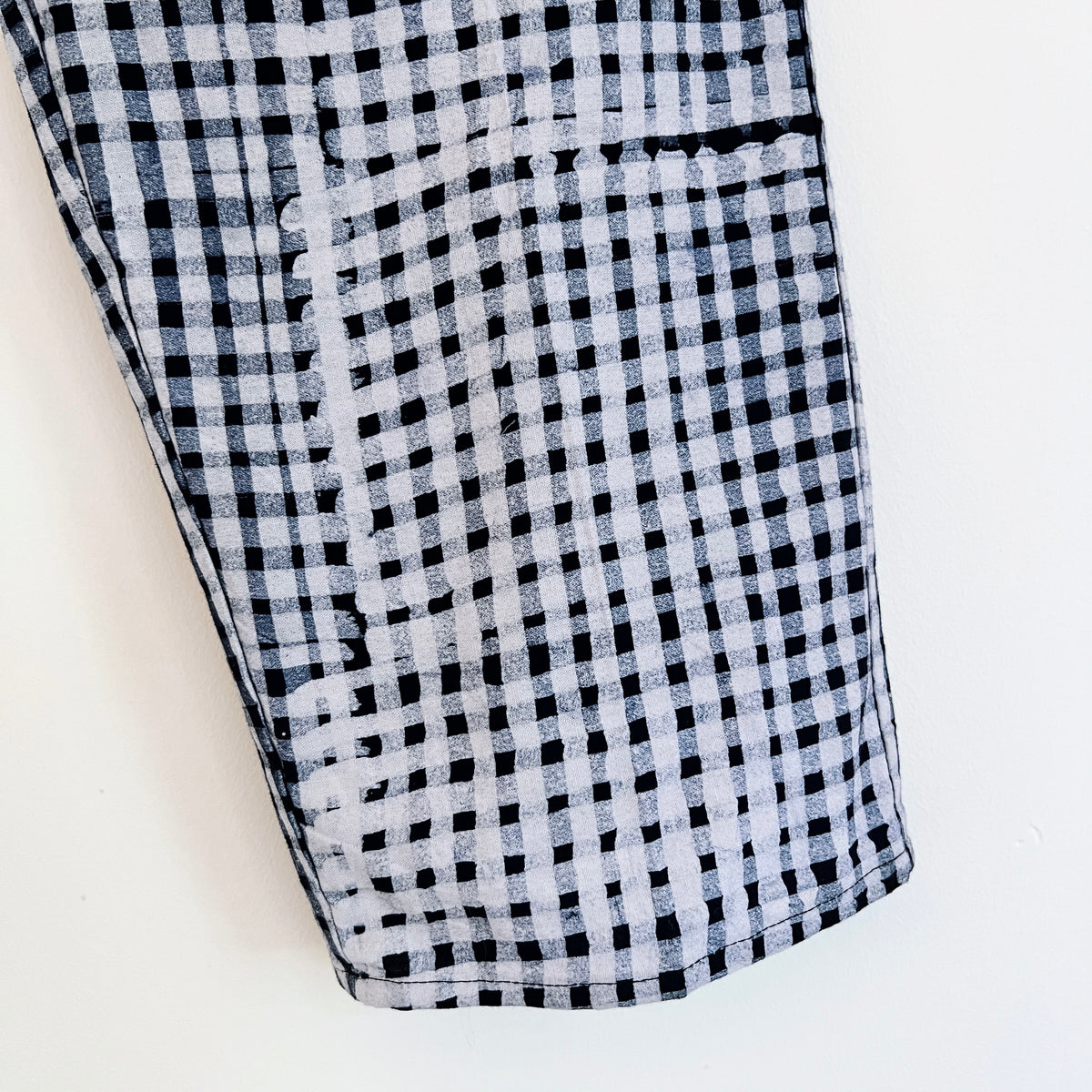 Close-up of the lower leg and hem of the Lazy Pants in Indigo Gingham, showing the hand-printed black and white gingham pattern on 100% cotton Batiki fabric with visible hand-dye texture and hemline detail

