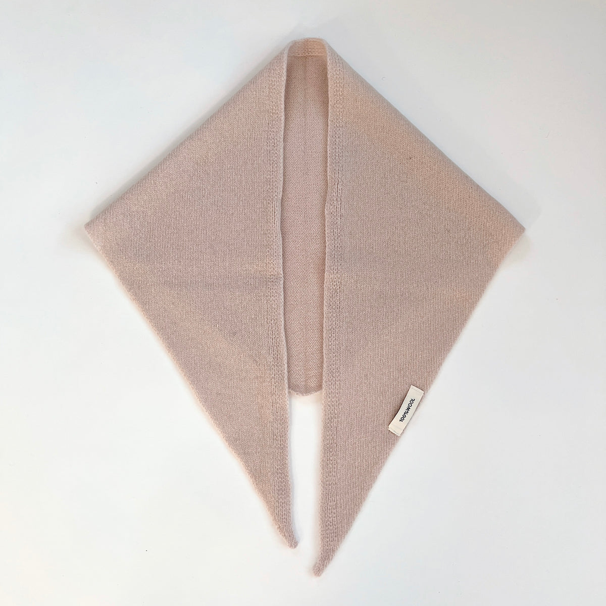 Flat lay view of the Cream merino wool triangle scarf with its long pointed ends hanging side by side.
