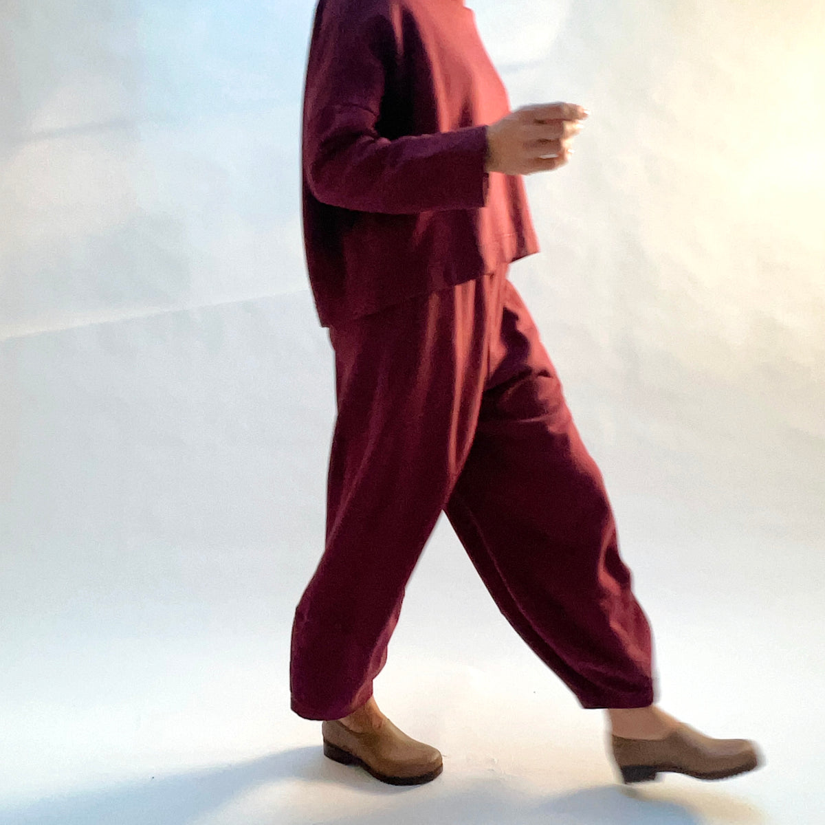 Model walking in Oliver Fleece Pant in Rhone, showing the loose drape and ankle-length silhouette.
