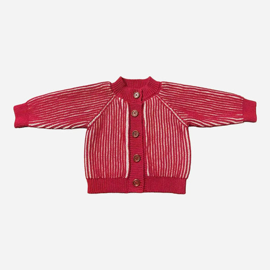Flat lay view of a red and cream brioche-knit cardigan with five wooden buttons, long sleeves and ribbed cuffs and hem.
