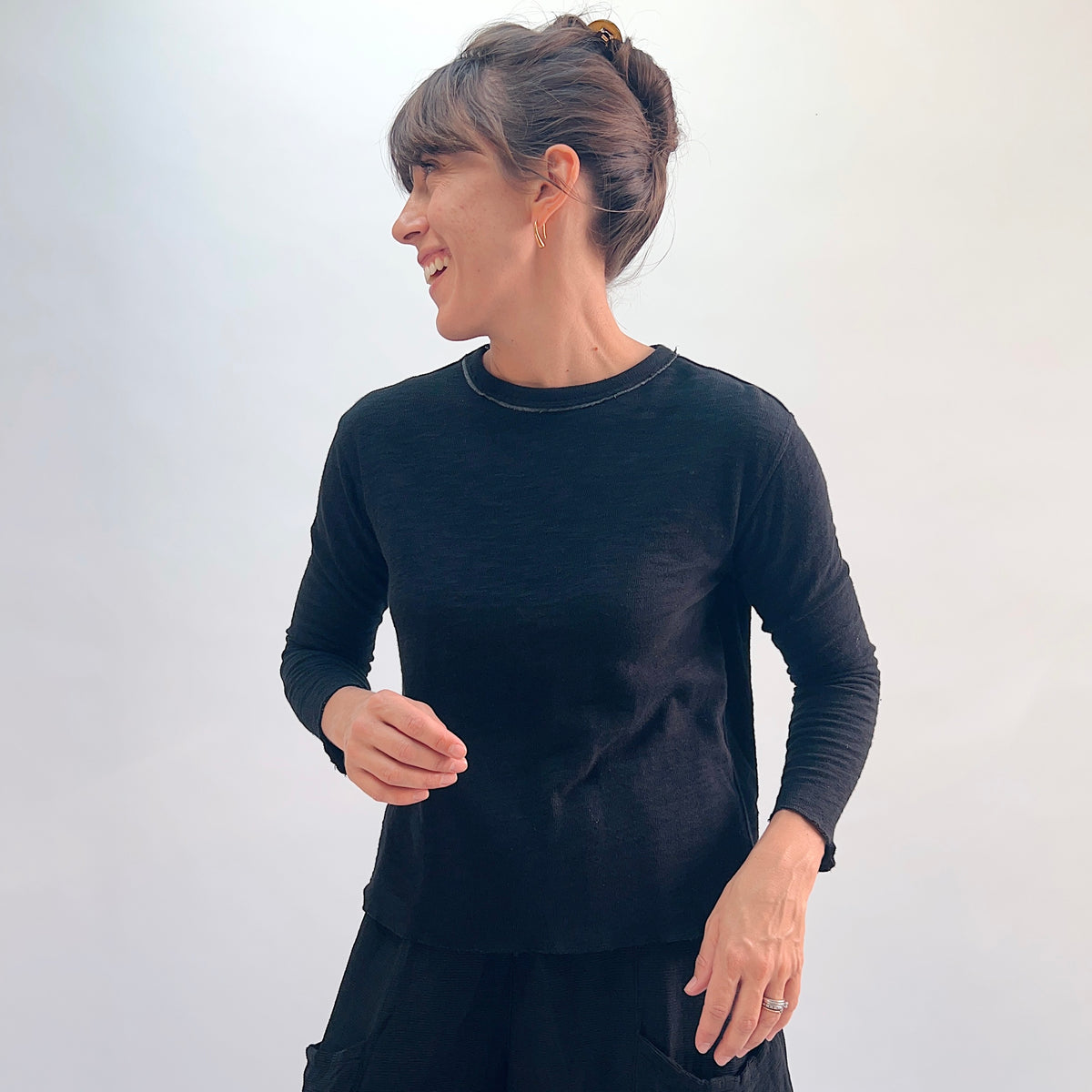 North Star Base Double Cotton Tee in Black, angled front view showing the relaxed double-layered long-sleeve silhouette with exposed raw-edge crew neckline
