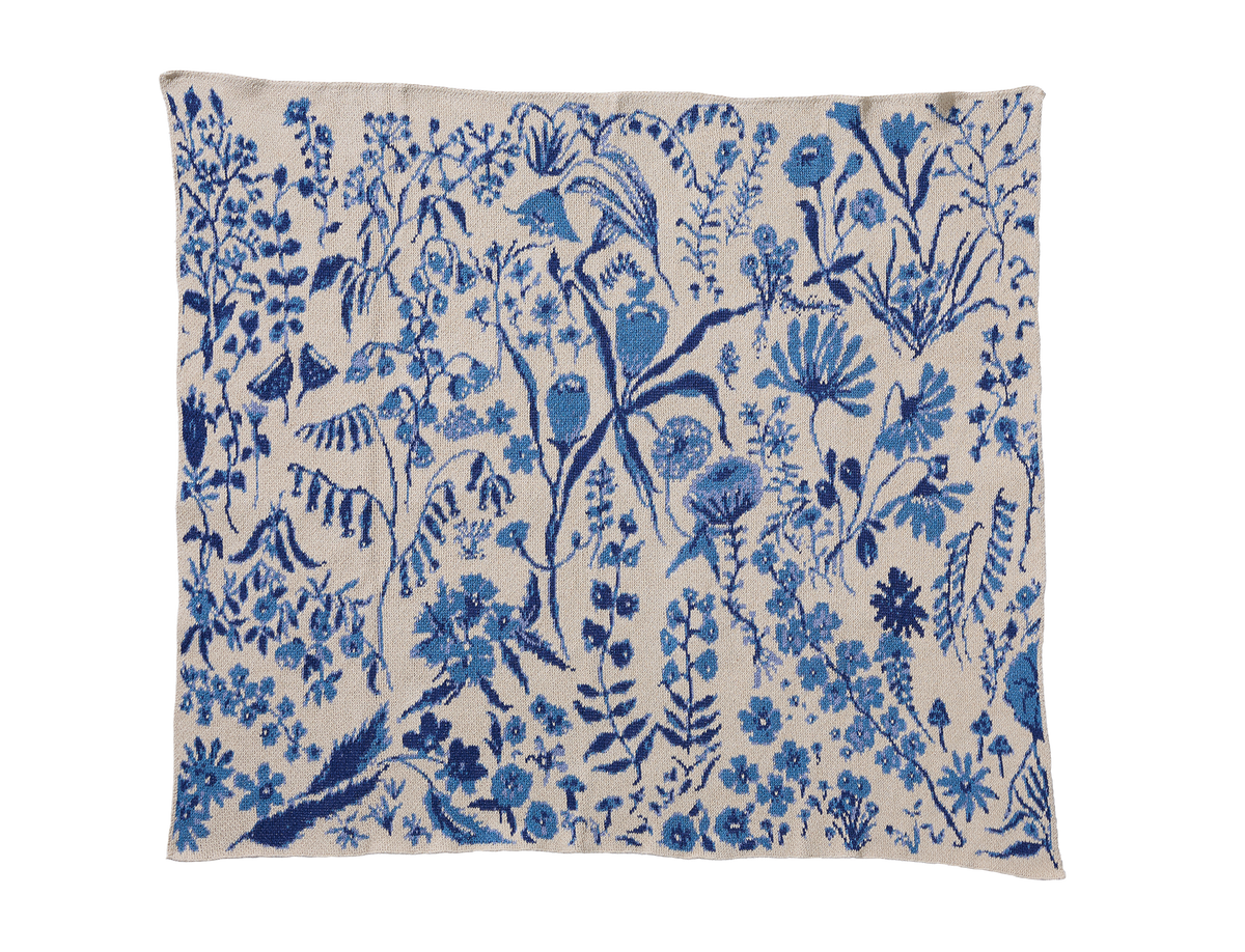 Flower Field Sky Blue child blanket laid flat, with light blue and navy flowers, leaves, and stems on cream.
