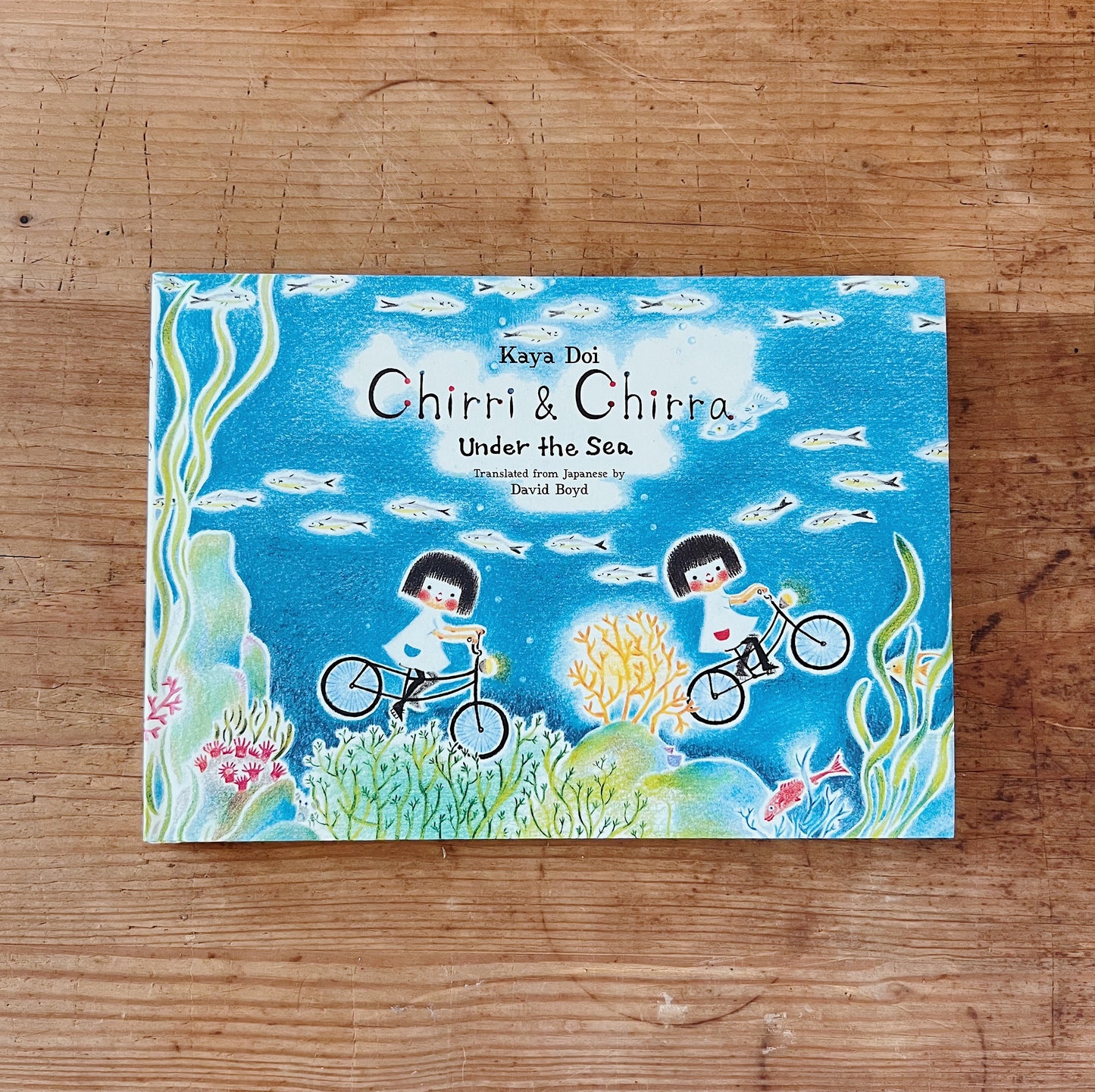 Hardcover book cover of 'Chirri & Chira: Under the Sea' featuring illustration of two characters on bicycles in an underwater scene with coral and fish.