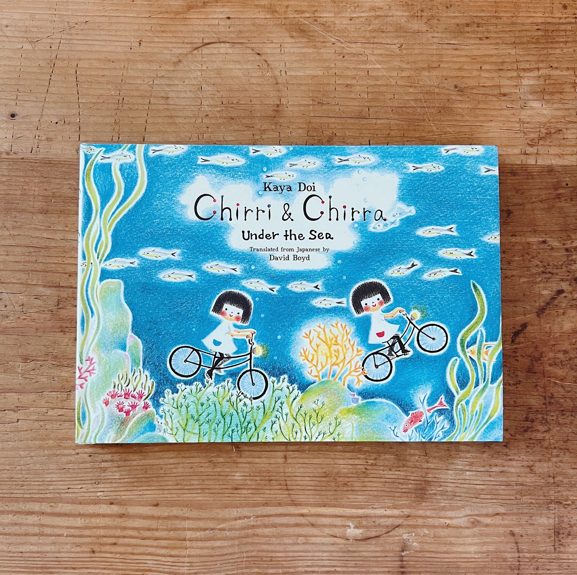 Hardcover book cover of 'Chirri & Chira: Under the Sea' featuring illustration of two characters on bicycles in an underwater scene with coral and fish.
