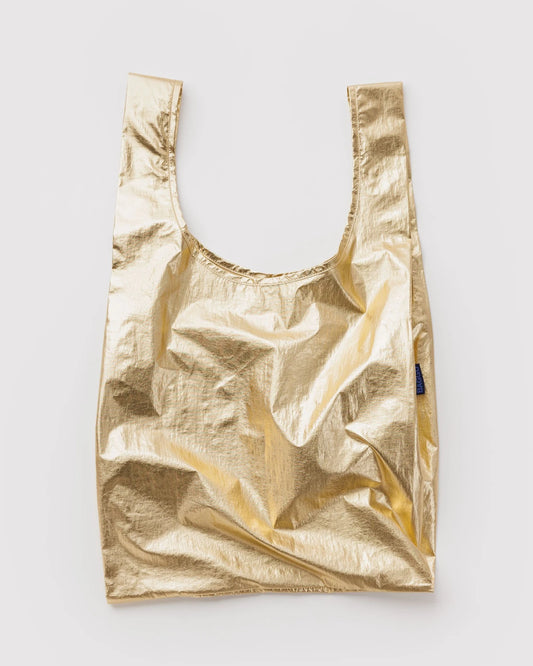 BAGGU Standard Baggu in Metallic Gold, shown unfolded with two handles and a shiny gold finish.
