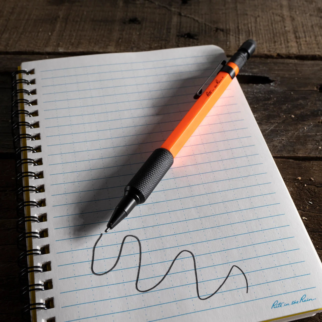 Orange pen with black cap on a notebook page with wavy line
