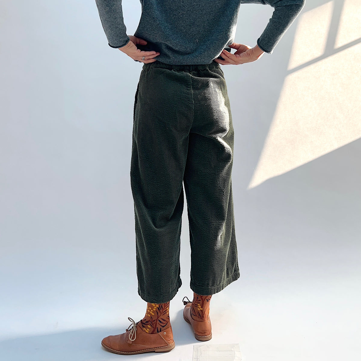 Back view of the Lux Corduroy Crop Wide Leg Pant in Kelp on a model, showing the waistband and vertical corduroy texture.
