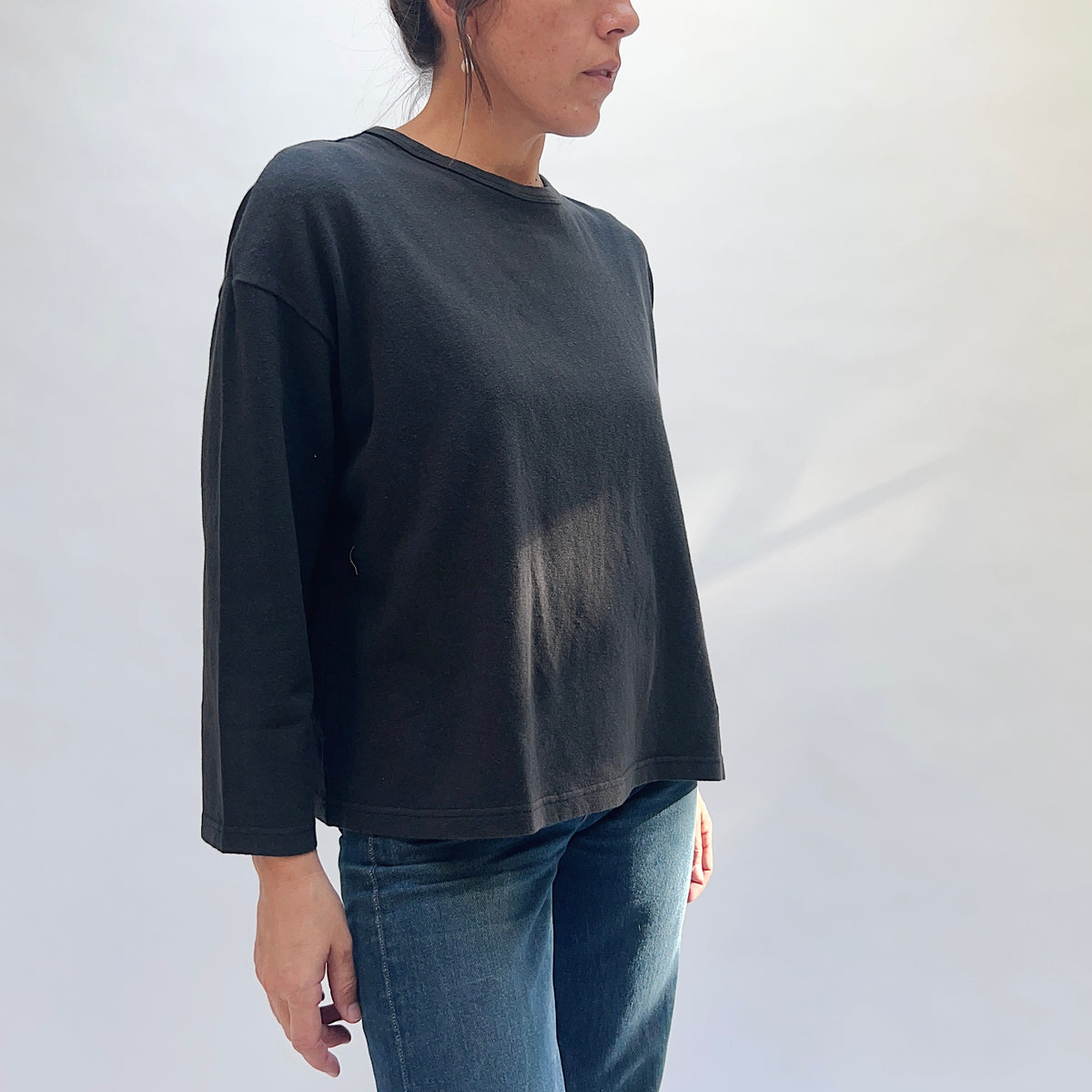 Front view of a model wearing the black cotton knit pullover, showing the round neckline, long sleeves, and straight hem.
