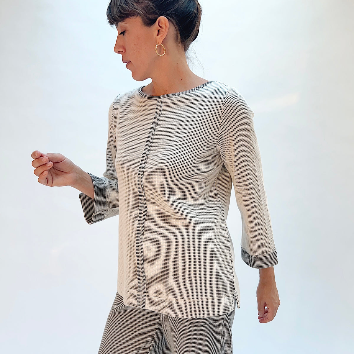Habitat Opposites Attract Seamed Pullover in Winter White, side view showing the center front seam, 3/4 sleeves with wide contrast cuff, and side slit in grid-textured thermal knit
