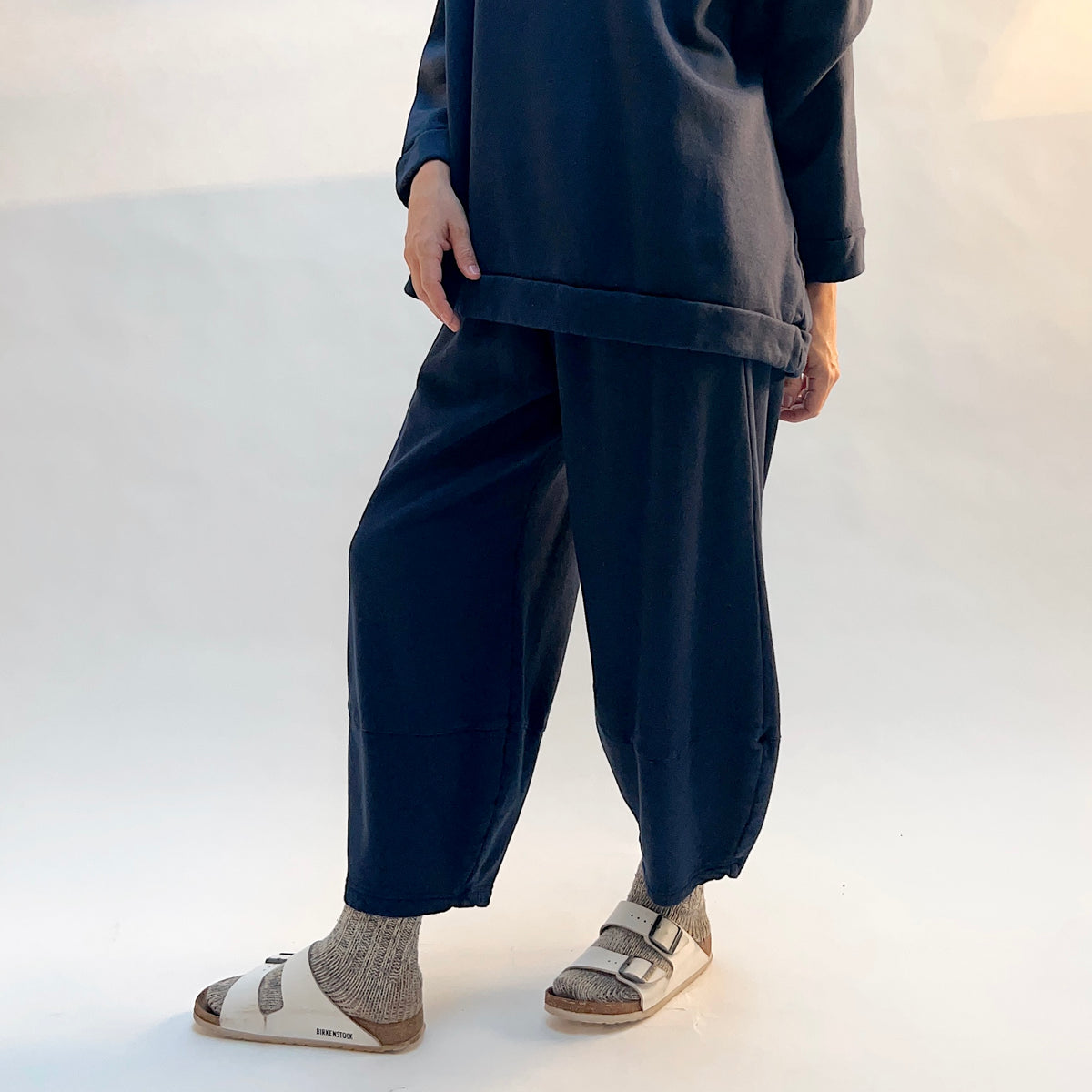 Angled front view of Bryn Walker Oliver Fleece Pant in Nova on a model, showing the rounded legs tapering toward the ankles.
