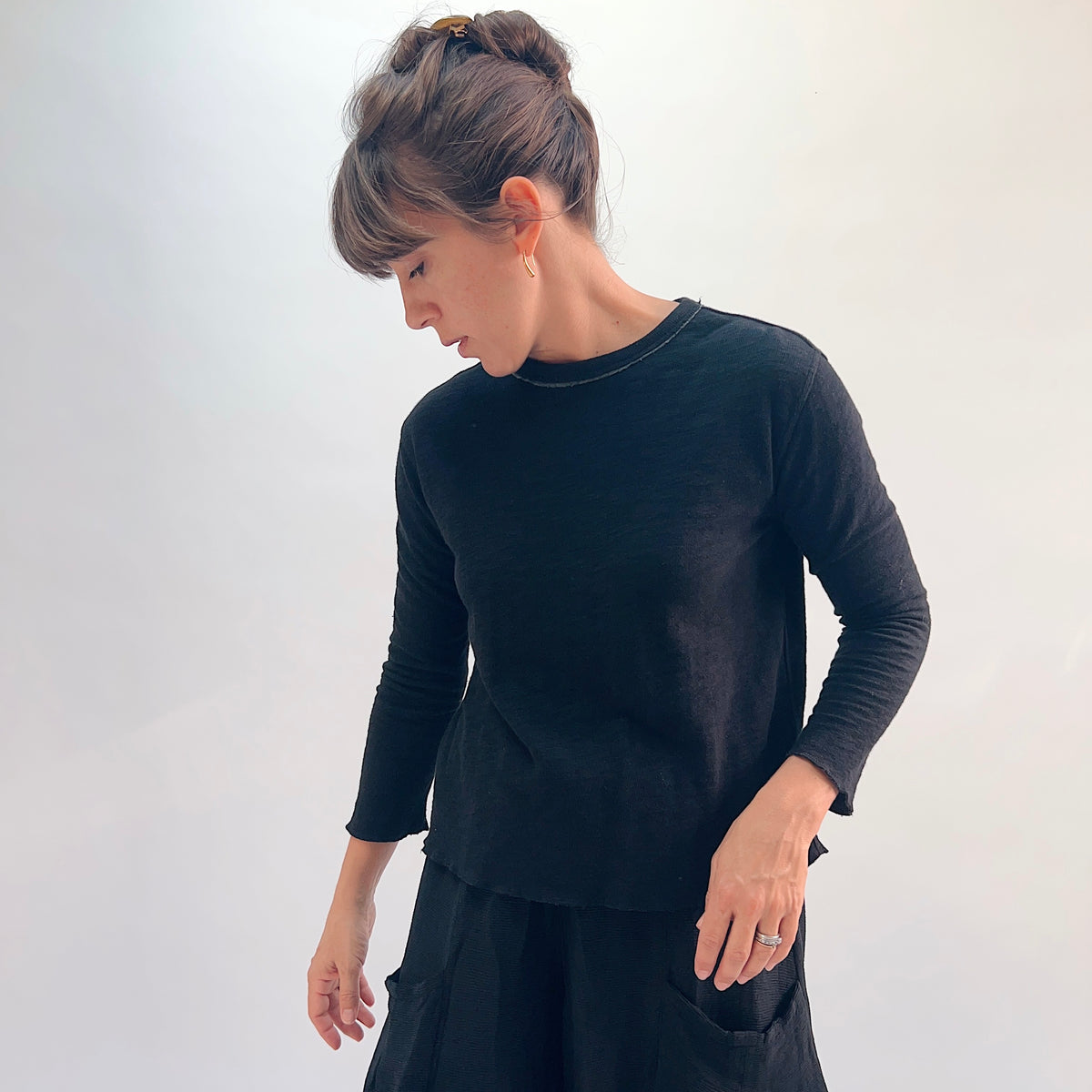 North Star Base Double Cotton Tee in Black, three-quarter front view showing the crew neckline with exposed raw-edge seam and double-layered knit fabric
