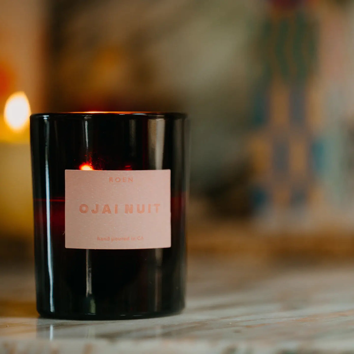 Black candle with a pink label on a blurred background