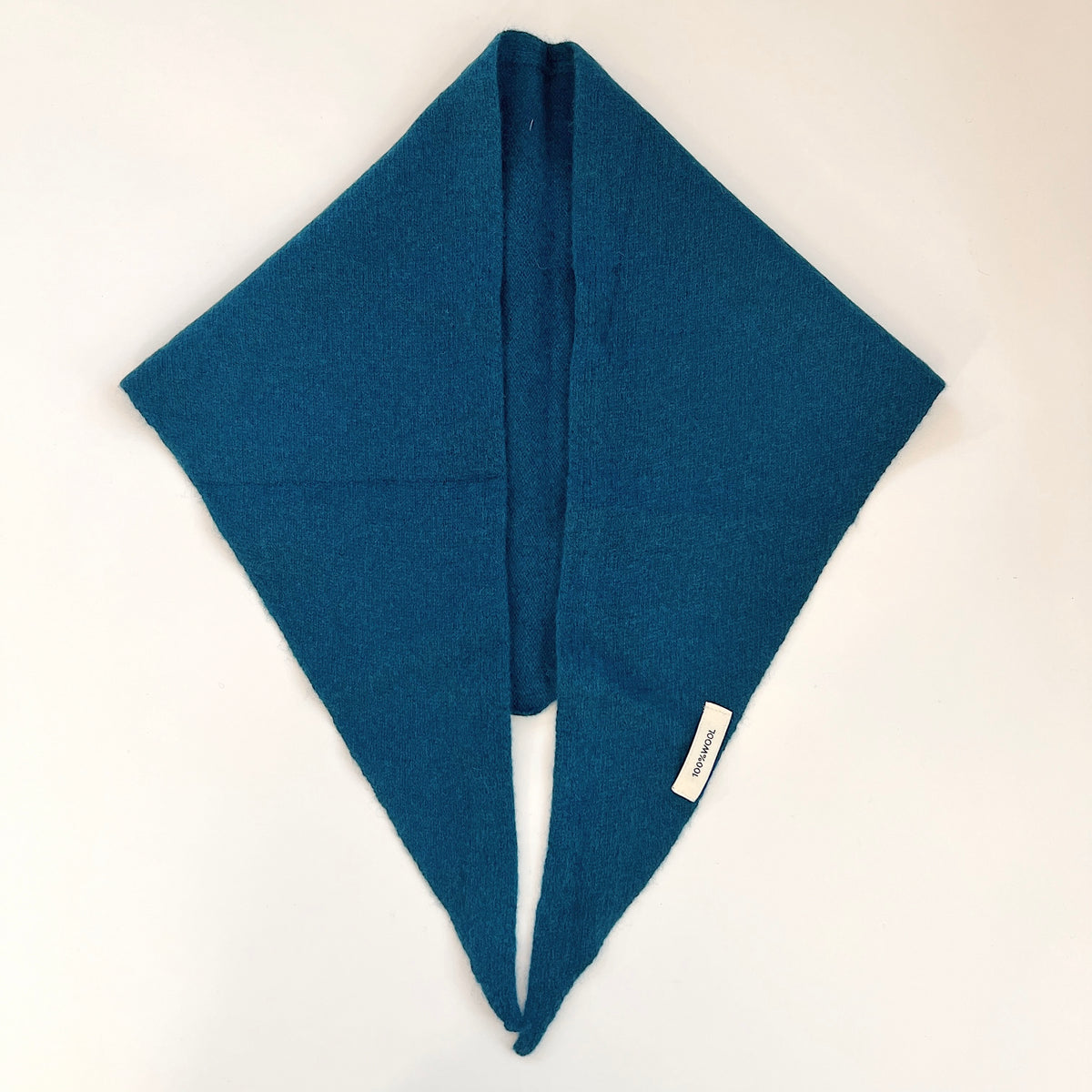 Ocean blue merino wool triangle scarf laid flat with long pointed ends side by side and a small white label.
