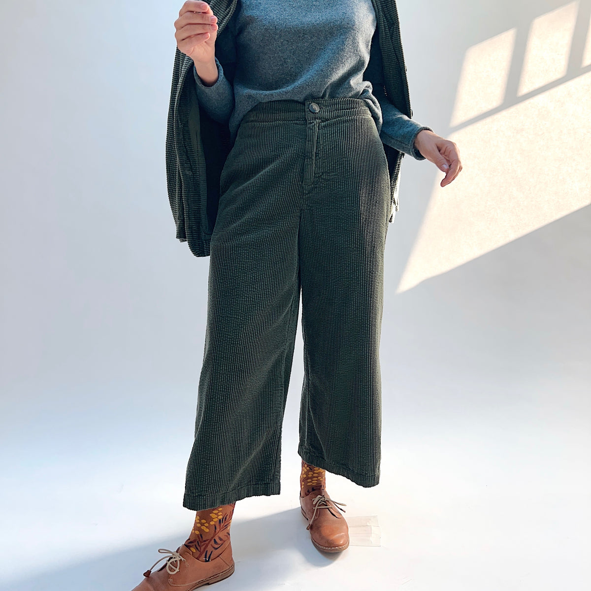 Front view of the Lux Corduroy Crop Wide Leg Pant in Kelp, showing the waistband button, front pockets, and cropped wide legs.
