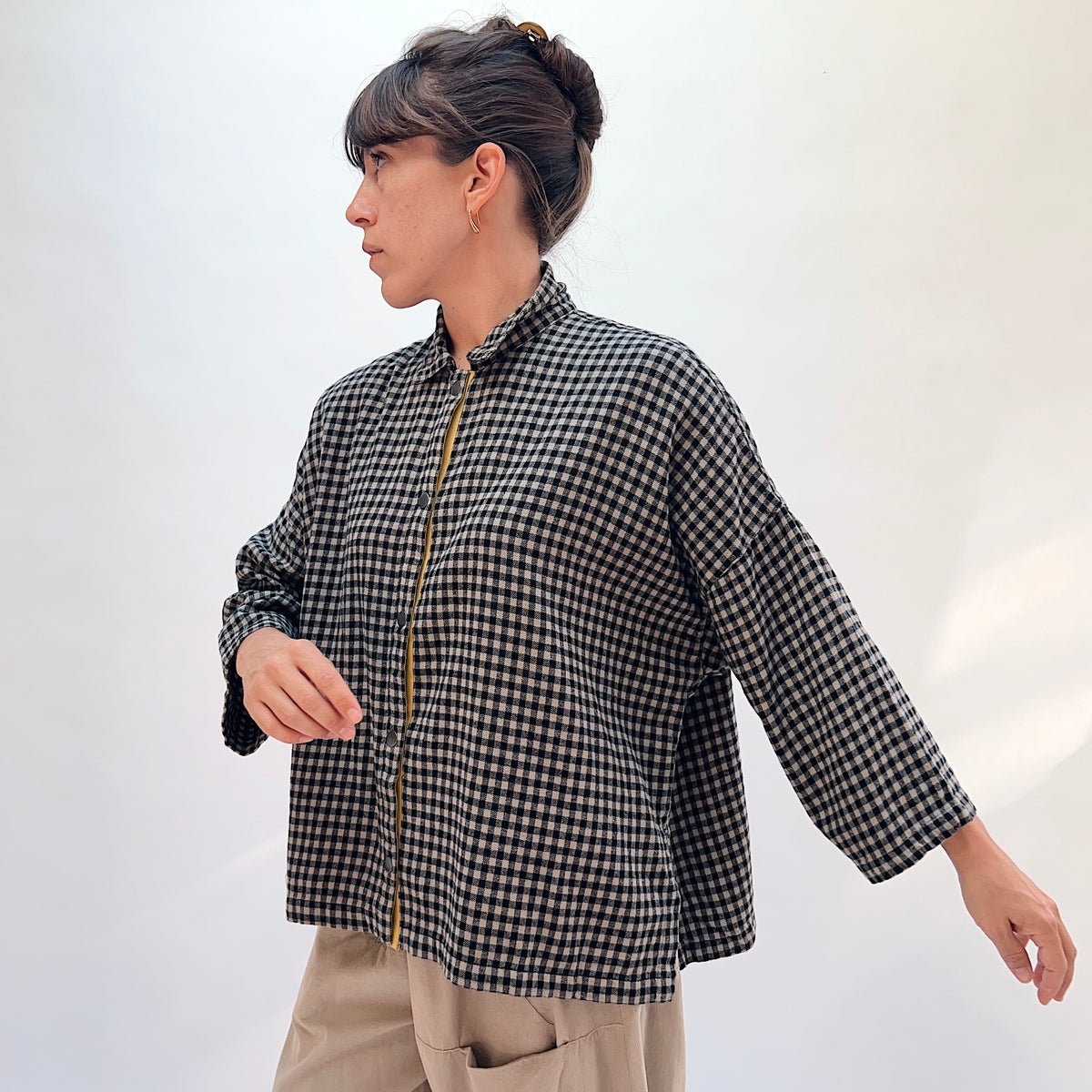 Eleven Stitch Small Check Big Shirt in Fennel, angled front view showing the stand collar, mustard contrast placket, chest pocket, and 3/4-length sleeves in black and natural small gingham check
