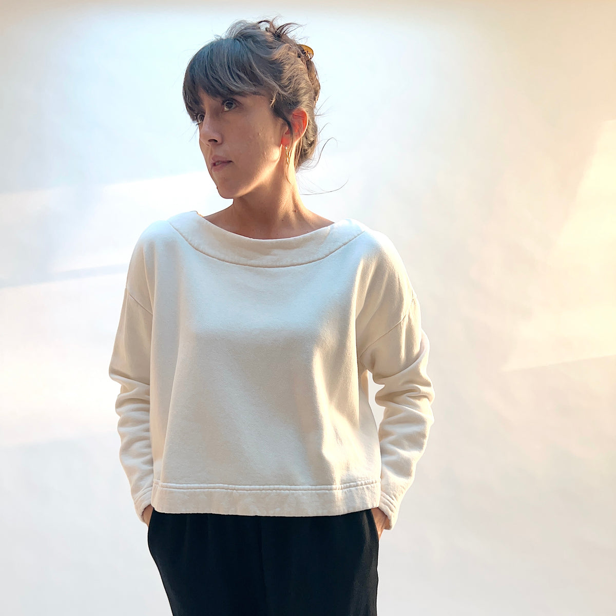 Model wearing Button Back Fleece Pullover in Cream with dark pants, showing the loose shape and long sleeves.

