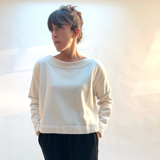 Model wearing Button Back Fleece Pullover in Cream with dark pants, showing the loose shape and long sleeves.
