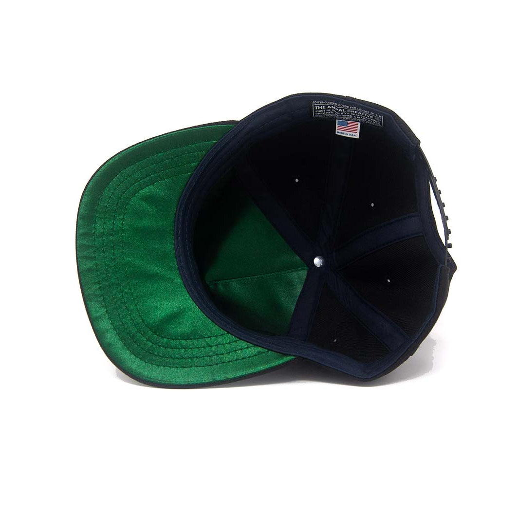 Interior view of the Ampal Creative Tiger III Black Snapback, showing the green satin underbrim and front panel lining, The Ampal Creative woven label with USA flag, and snapback closure, on a white background
