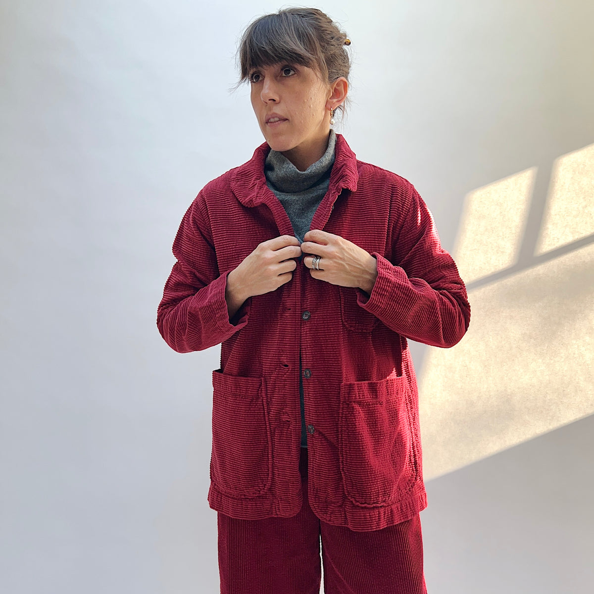 Model wearing the Lux Corduroy Long Blazer in Maraschino with the collar folded down and the front partly open.
