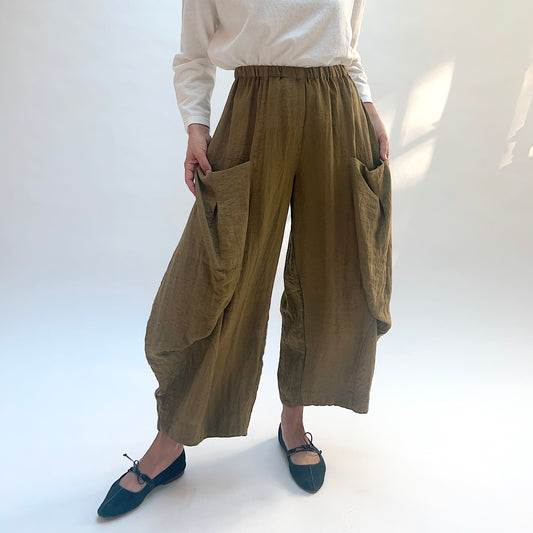 Eleven Stitch Double Pocket Crinkle Travel Pant in Olive, front view with model holding the large side pockets open.
