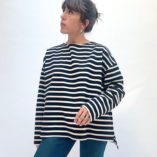 Front view of a model wearing the black and natural striped knit pullover, showing the wide neckline and long sleeves.
