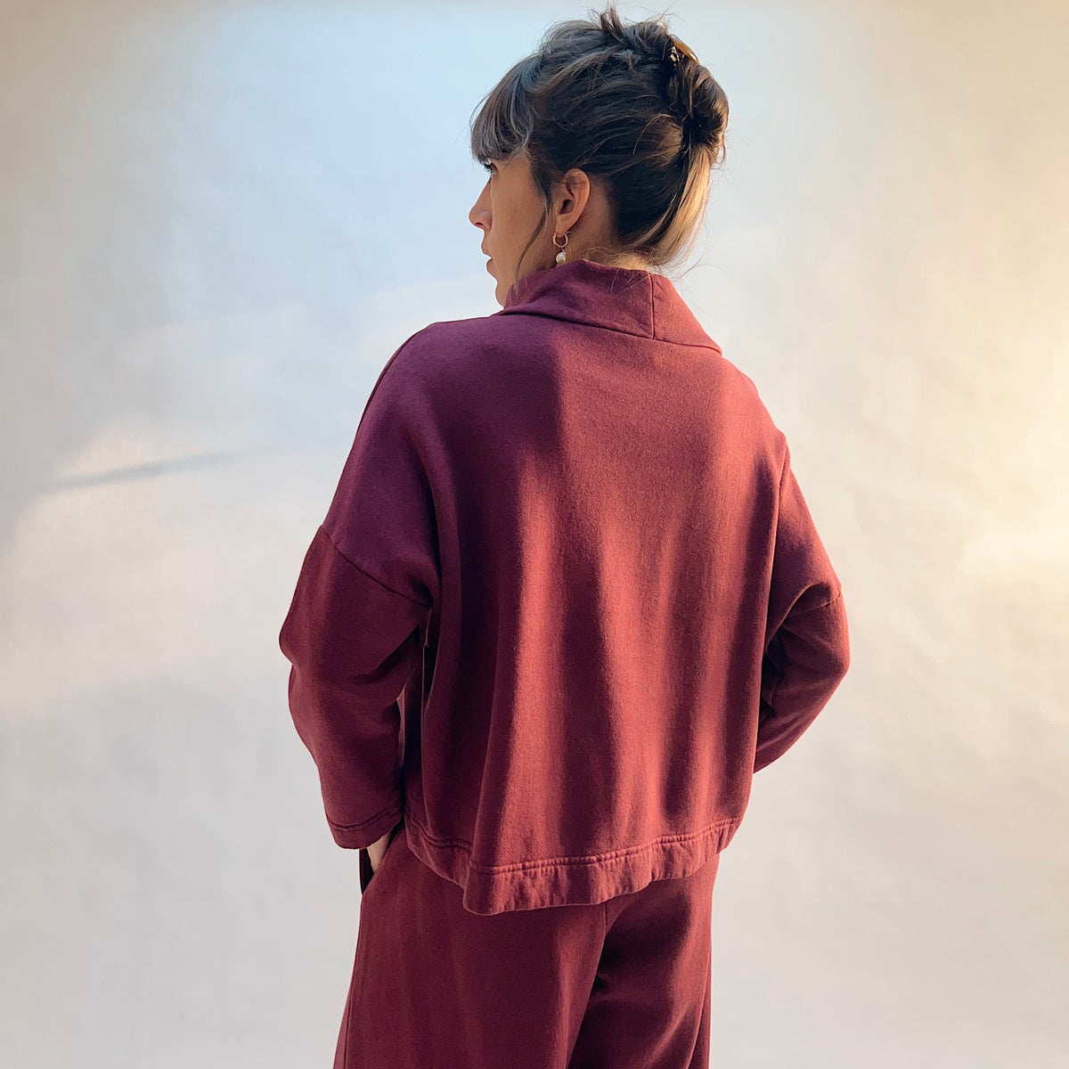 Angled back view of Cropped Fleece Stowe Sweatshirt in Rhone, showing the raised collar, dropped shoulders, and cropped hem.
