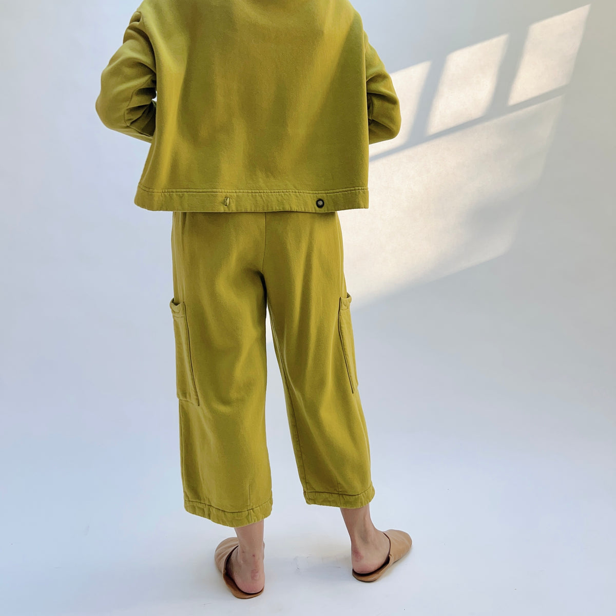 Back view of Pasha Fleece Pant in Chartreuse on a model, showing the loose cropped legs.

