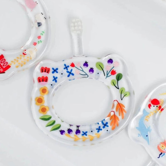A colorful baby toothbrush with a floral pattern on the handle, designed for safe and effective brushing for ages 5-24 months.