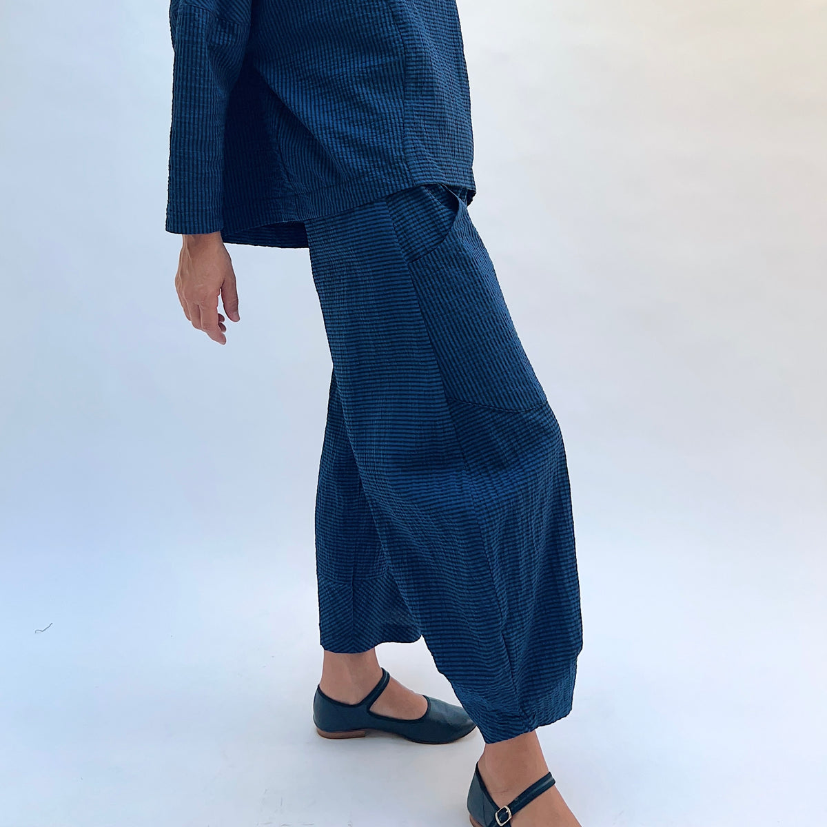 Niche Izzie Pant in Blue Seersucker Stripe, side view showing the relaxed hip and tapered ankle in teal and black seersucker stripe
