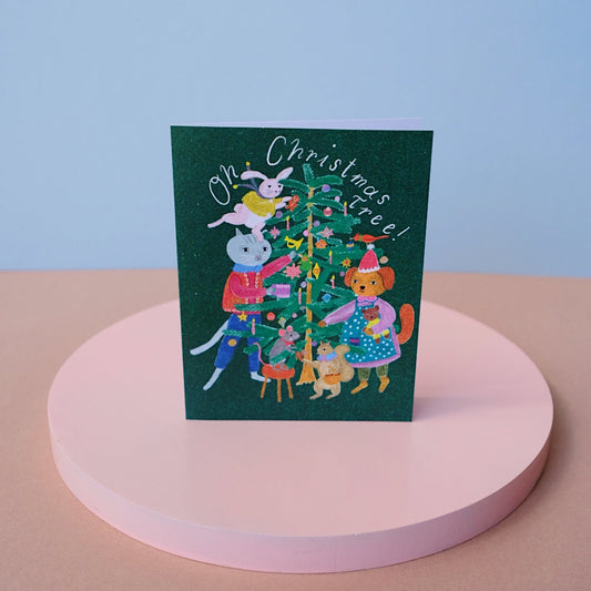 Small Adventure Christmas Tree Card, illustrated animals decorating a Christmas tree beneath the words “Oh Christmas Tree!” on a dark green background.
