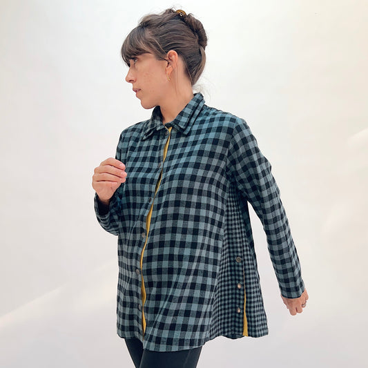 Eleven Stitch Placket Gusset Shirt in Dusty Denim, three-quarter front view showing the oversized silhouette in dusty blue and black gingham check with high funnel collar and mustard contrast placket
