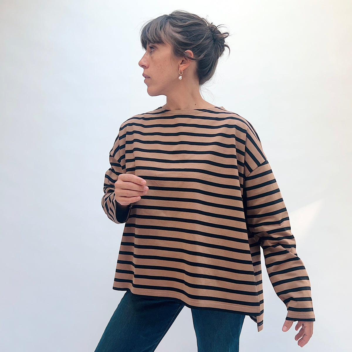 Model wearing the mocha and navy striped knit pullover, showing the front, dropped shoulders, and extended sleeve.
