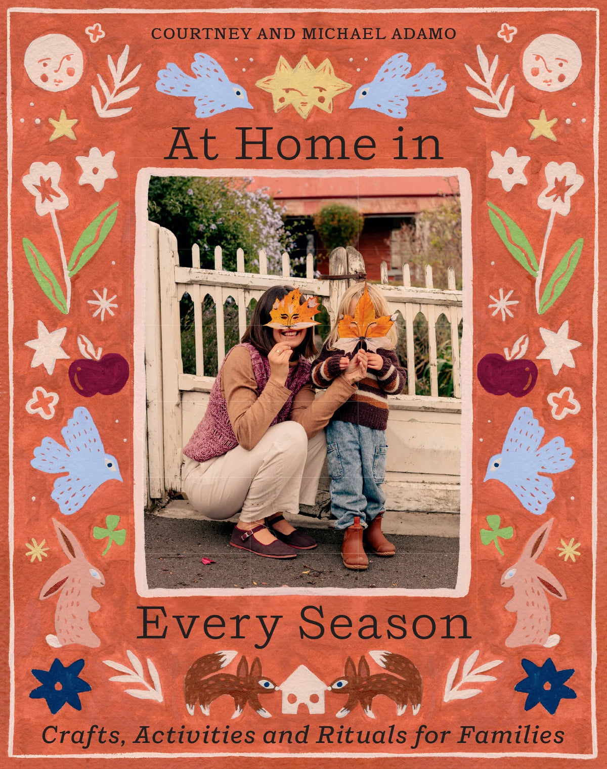 Cover of At Home in Every Season by Courtney and Michael Adamo, with colorful nature illustrations framing an adult and child holding autumn leaves.
